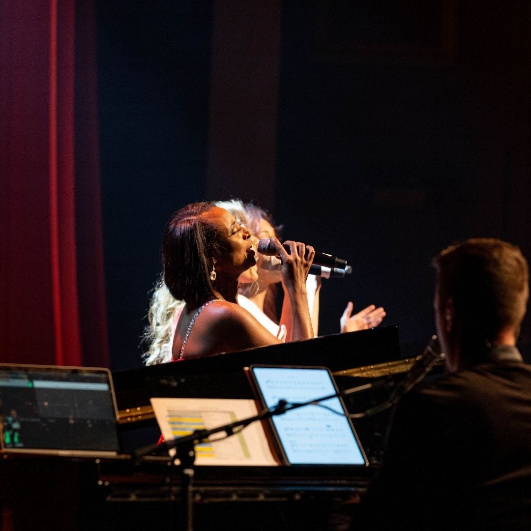 woman singer next to band on stage